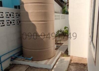 Side yard with large water storage tank and minimal landscaping
