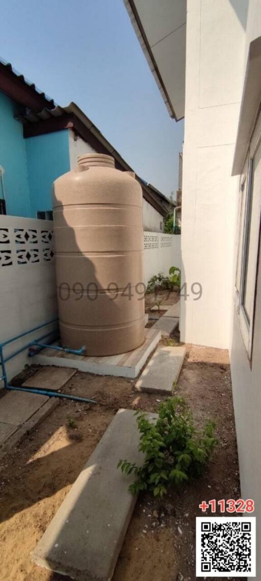 Side yard with large water storage tank and minimal landscaping