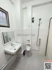 Compact white tiled bathroom with sink, toilet and shower