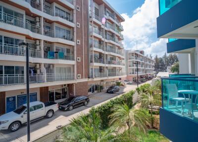 Exterior view of a modern apartment building with balconies and parked cars