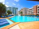 Spacious communal swimming pool with sun loungers and modern apartment buildings
