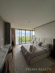 Modern bedroom with large windows and a view, featuring a comfortable bed and a dog