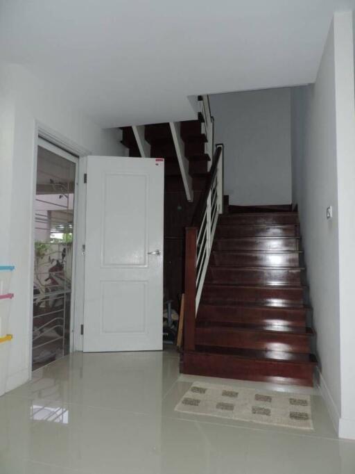 Bright entryway with polished floor tiles and wooden staircase