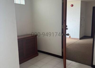 Brightly lit house corridor with white tiled flooring and wooden doors