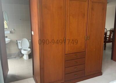 Wooden wardrobe in a bedroom with open door to en-suite bathroom