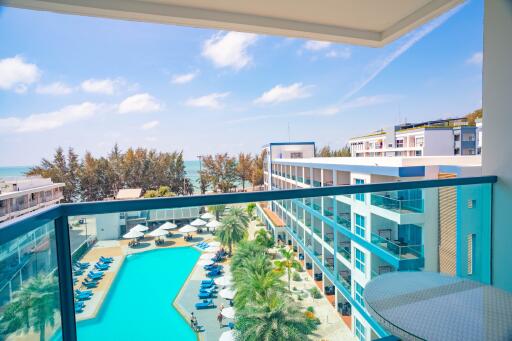 Balcony view of a luxurious residential complex with a swimming pool and sea view