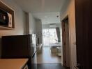 Modern apartment interior view showing a compact kitchen leading into a bright living space