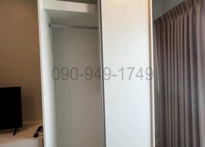 Sliding door wardrobe in a modern bedroom with curtains and partial view of a TV