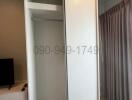 Sliding door wardrobe in a modern bedroom with curtains and partial view of a TV