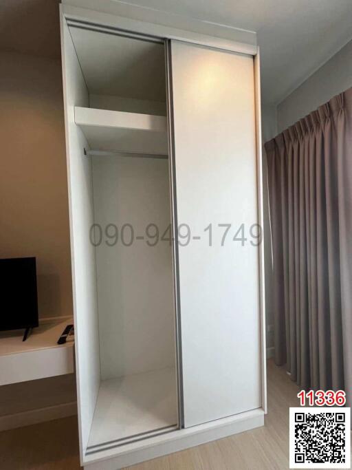 Sliding door wardrobe in a modern bedroom with curtains and partial view of a TV