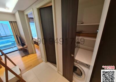 Compact interior space with shelving, washer, and sliding door leading to another room