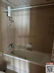 Moderately lit bathroom with bathtub, wall tiles, and shower area.