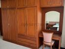 Spacious bedroom with wooden wardrobe and dressing table