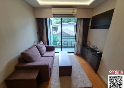 Cozy living room with a comfortable sofa and a television set, leading to a balcony