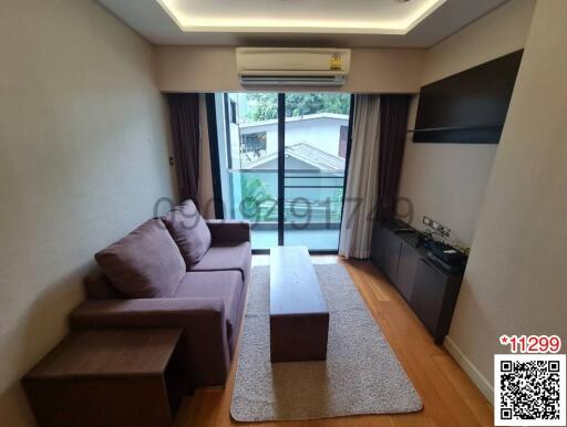 Cozy living room with a comfortable sofa and a television set, leading to a balcony