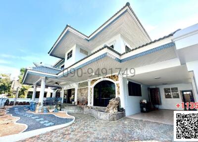 Elegant two-story house with blue tile roofing and a spacious cobblestone driveway