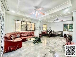 Spacious living room with a large red leather sofa and marble flooring