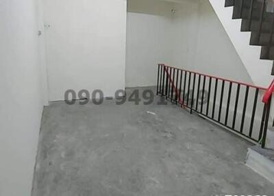 Empty staircase area with white walls and red handrails