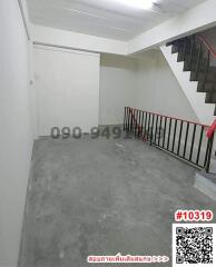 Empty staircase area with white walls and red handrails