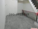 Empty staircase area with white walls and red handrails