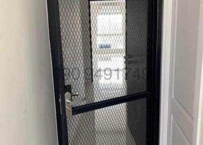 Black metal security door with mesh screen in the entryway of a home