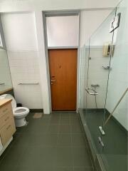 Spacious bathroom with modern glass shower stall, tiled walls and flooring