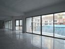 Spacious unfurnished room with large windows overlooking a swimming pool