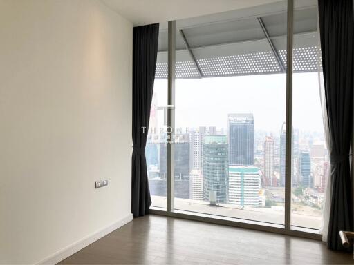 Spacious bedroom with large window providing cityscape view