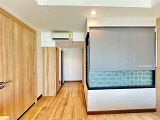 Bright corridor with wooden flooring leading to rooms with sliding door and built-in cabinets