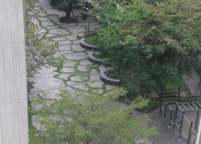 View from a window showing a well-maintained communal garden with walking paths in an apartment complex
