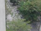 View from a window showing a well-maintained communal garden with walking paths in an apartment complex