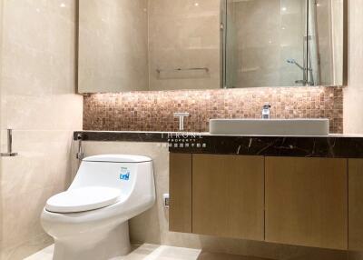 Modern bathroom with toilet, sink, and vanity mirror