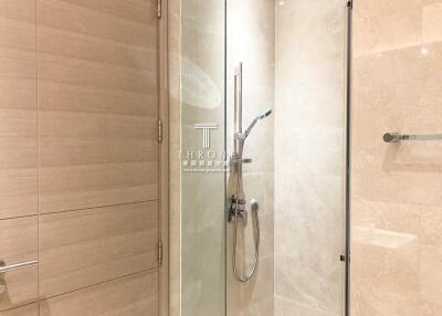 Modern bathroom with glass shower enclosure and beige tiles