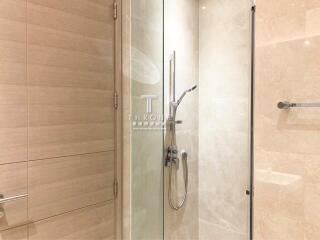 Modern bathroom with glass shower enclosure and beige tiles