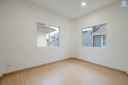 Spacious and well-lit empty bedroom with hardwood floors and two windows