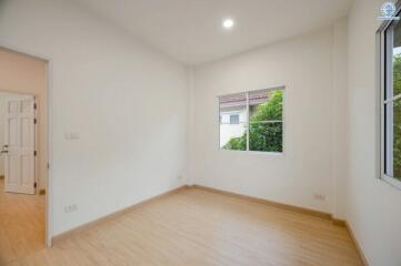 Bright empty bedroom with hardwood floors and a garden view window