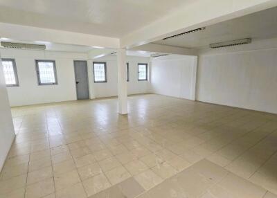 Spacious empty indoor space with tiled flooring and multiple windows