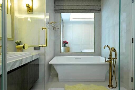 Modern bathroom with white bathtub, elegant fixtures, and glass shower