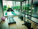 Home gym with modern exercise equipment and view of the pool