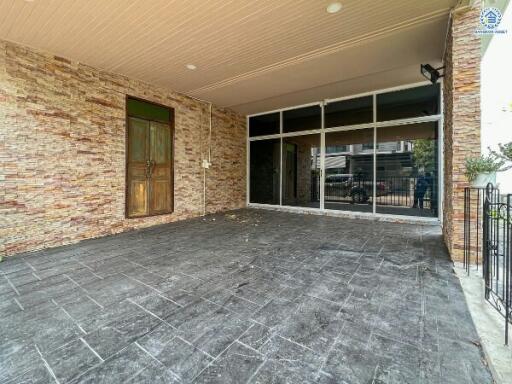 Spacious tiled patio with brick wall and glass door entrance