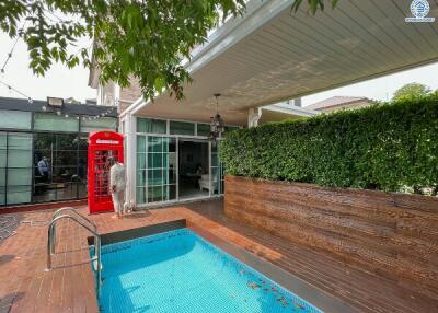 Spacious backyard with a swimming pool, wooden decking, and a unique red phone booth