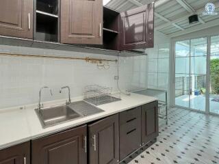 Modern kitchen with stainless steel sink, dark wood cabinets, and patterned floor tiles