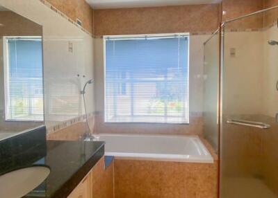 Spacious bathroom with natural light featuring a tub and a glass shower
