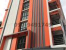 Modern multi-story residential building with vibrant orange and white facade