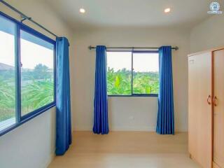 Bright bedroom with a view of greenery and blue curtains