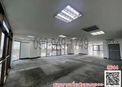 Spacious empty commercial space with large windows and concrete flooring