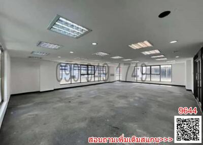 Spacious empty office space with large windows and carpet flooring