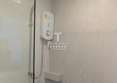 Modern bathroom with wall-mounted electric shower unit and tiled walls