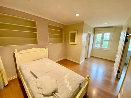 Cozy bedroom with built-in shelves and hardwood floor