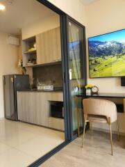 Modern kitchen with open glass door and wall-mounted television